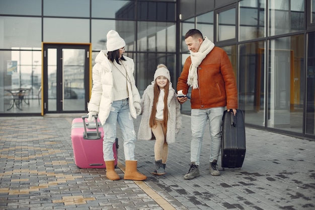 Mãe pai e filha com bagagem saindo do terminal do aeroporto