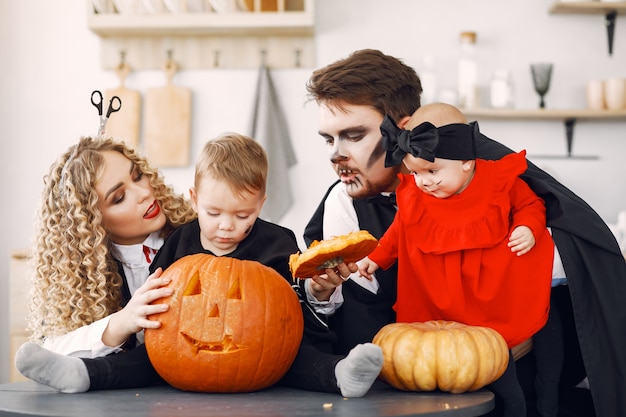 Mãe, pai e filhos em fantasias e maquiagem. Família se prepara para a celebração do Halloween.