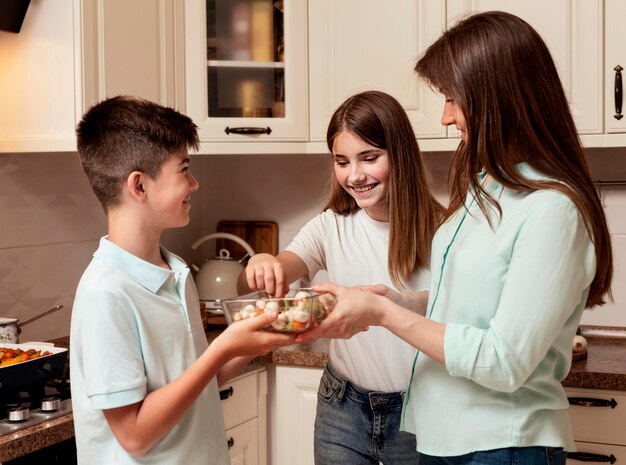 Mãe preparando comida na cozinha com crianças