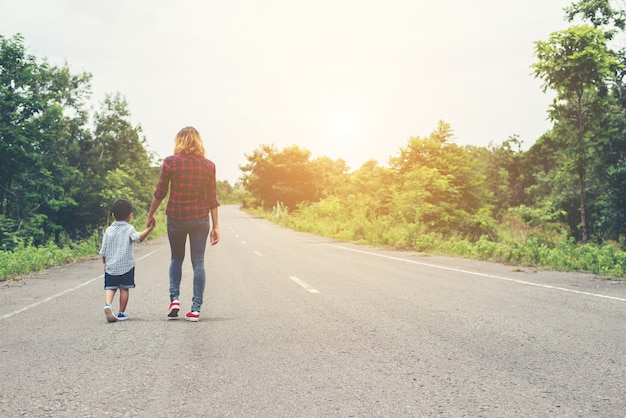 Mãe segurando a mão de seu filho no dia de verão andando na rua