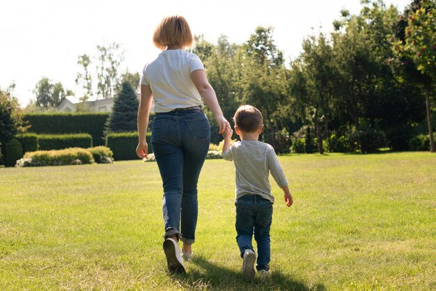 Mãe segurando a mão do filho por trás