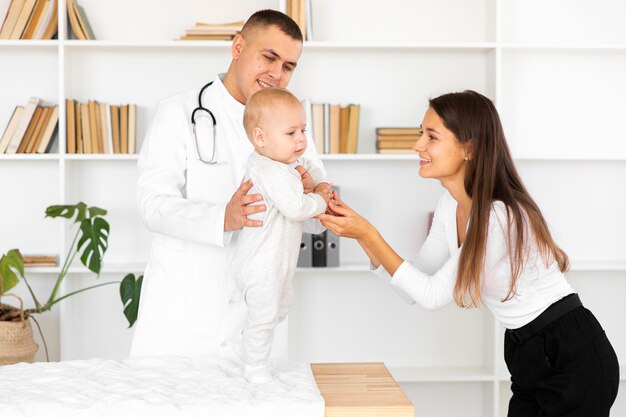 Mãe, segurando as mãos do bebê no exame médico