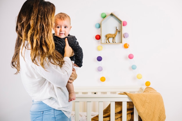 Mãe segurando o bebê perto do berço