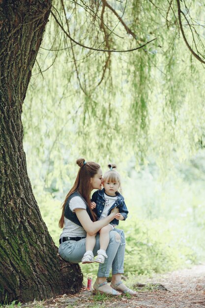 Mãe sentada em uma árvore com a filha sentada em suas pernas