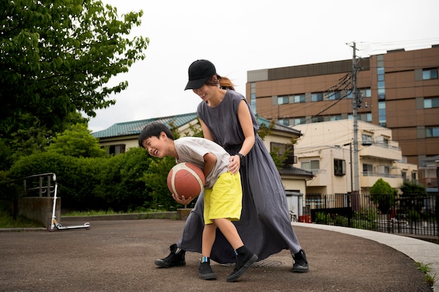 Mãe solteira jogando basquete com o filho