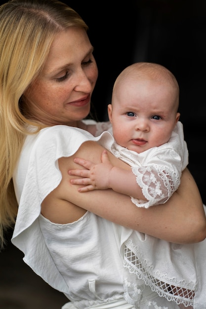 Foto grátis mãe sorridente com foto média segurando o bebê