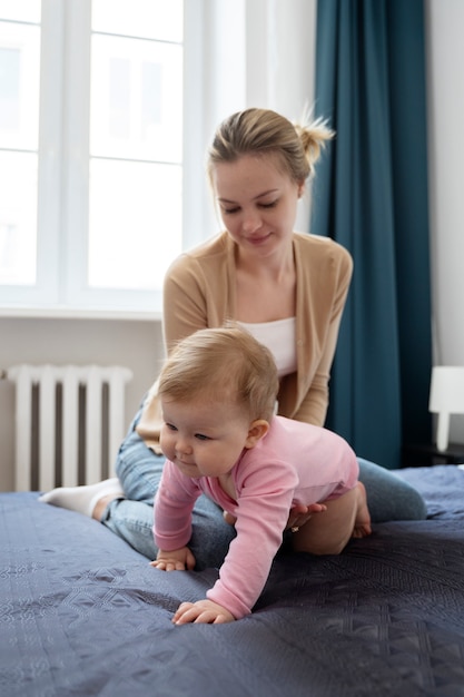 Mãe sorridente de tiro completo ajudando o bebê a engatinhar