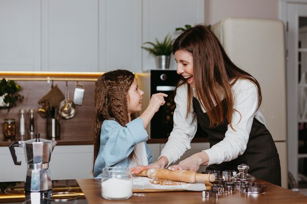 Mãe sorridente e filha cozinhando juntas na cozinha