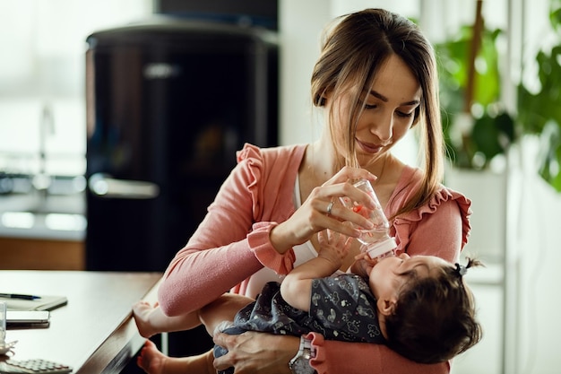 Foto grátis mãe sorridente usando mamadeira e dando água para sua filha bebê