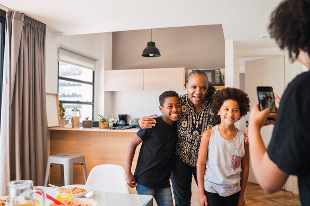 Mãe tirando foto da avó com os netos em casa