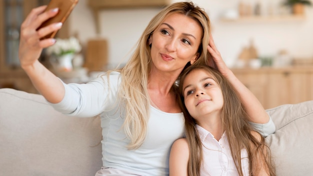 Mãe tirando selfie com a filha em casa