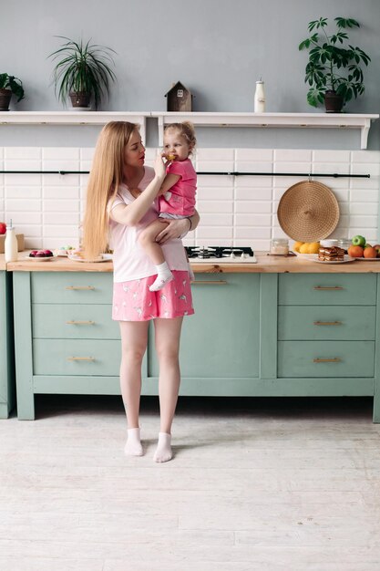 Mãe tomando café da manhã com sua linda filha na cozinha