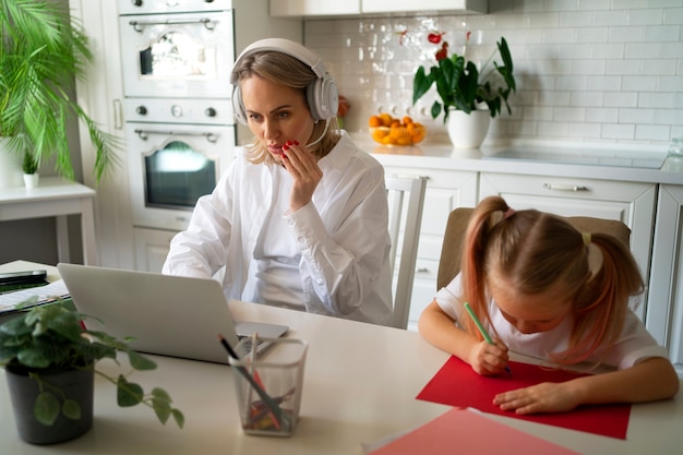 Foto grátis mãe trabalhando em casa tentando equilibrar a vida familiar com a criança e o trabalho