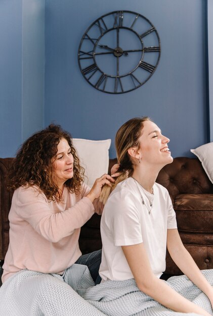 Mãe trançando o cabelo da filha sorridente