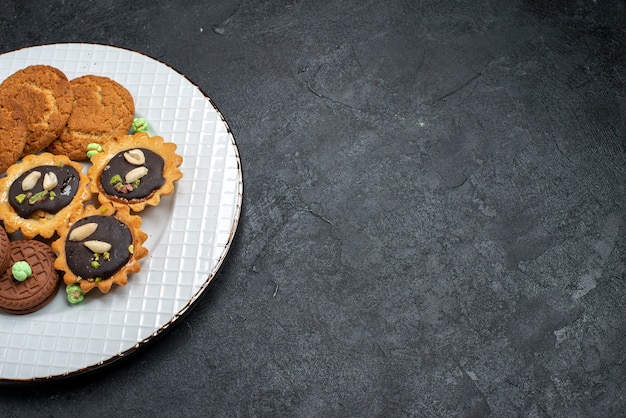Mais de perto, de cima para baixo, diferentes cookies, biscoitos doces e deliciosos na superfície cinza.