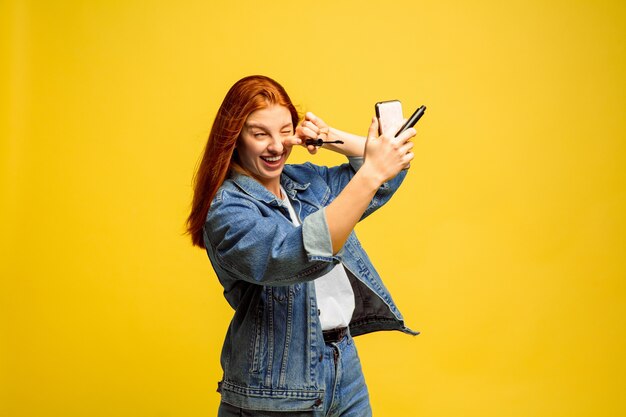 É mais fácil ser seguidor. Não precisa de selfie para maquiagem. Retrato de uma mulher caucasiana em fundo amarelo. Modelo de cabelo vermelho feminino lindo. Conceito de emoções humanas, expressão facial, vendas, anúncio.