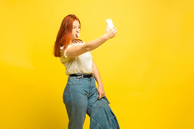 É mais fácil ser seguidor. Precisa de roupas mínimas para selfie. Retrato de uma mulher caucasiana em fundo amarelo. Modelo de cabelo vermelho feminino lindo. Conceito de emoções humanas, expressão facial, vendas, anúncio.