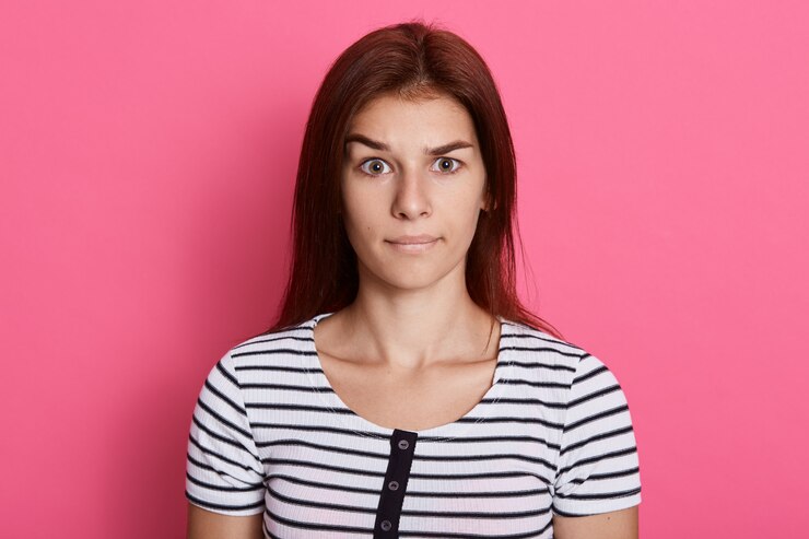 Foto grátis mal-entendido senhora, vestindo camiseta listrada casual, posando isolado sobre uma parede rosa, com olhar sério.