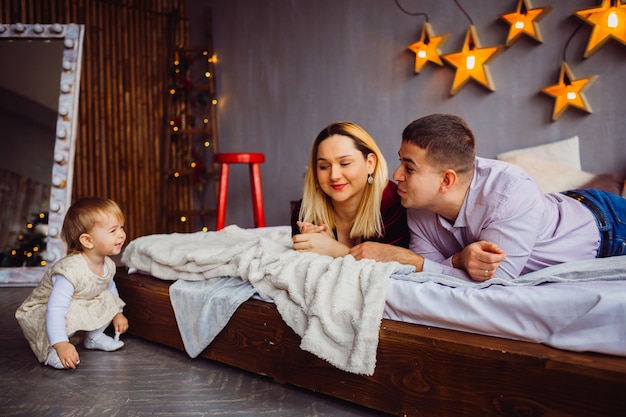 Mamãe e papai sorriem para a menina deitada na cama