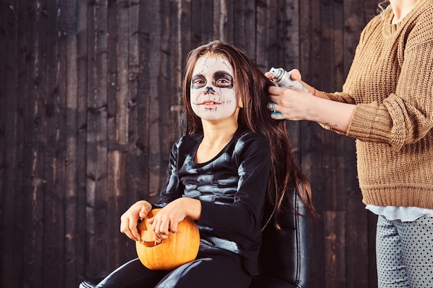 Mamãe faz penteados com spray de cabelo para festa de halloween. conceito de dia das bruxas.