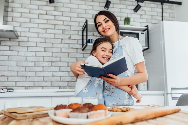 Mamãe fica com o livro de receitas e preparando comida com a filha