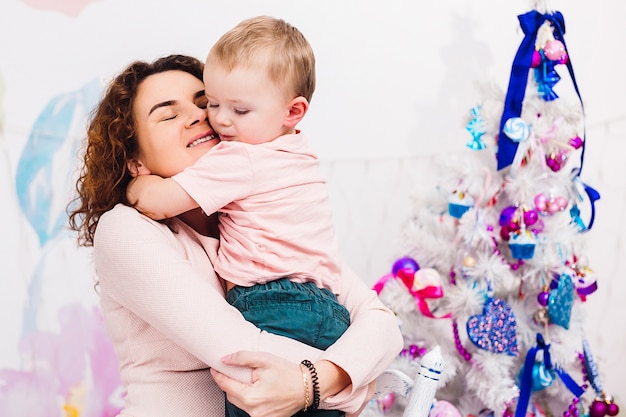 Mamãe se diverte com o filho sentado no quarto vestido para o Natal e Ano Novo