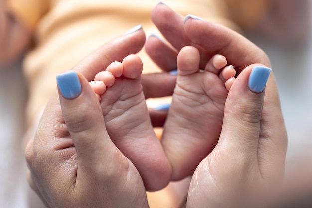 Foto grátis mamãe segura as pernas de um bebê recém-nascido em suas mãos