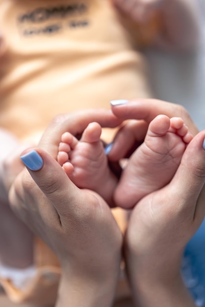 Mamãe segura as pernas de um bebê recém-nascido em suas mãos