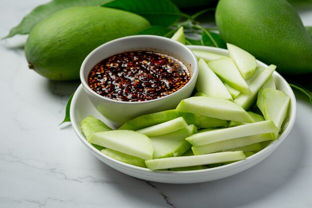 Manga verde fresca com molho de peixe doce mergulhando na superfície branca