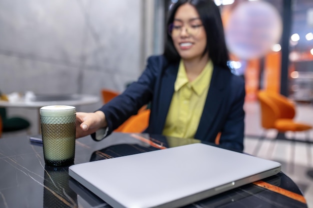 Manhã de negócios. Mulher de negócios asiáticos no escritório tomando café da manhã