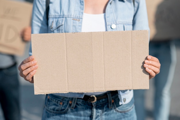 Manifestante de close-up, segurando a placa com maquete