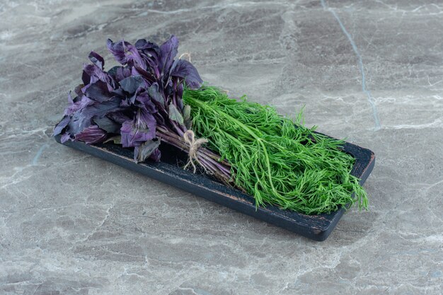 Manjericão roxo e endro na bandeja, na mesa de mármore.