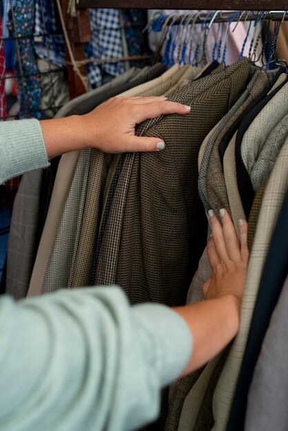 Mão à procura de blazer no mercado de segunda mão