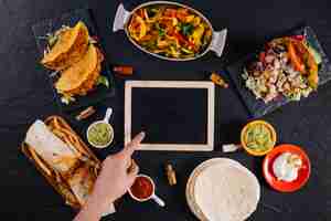 Foto grátis mão apontando no quadro negro em meio à comida mexicana