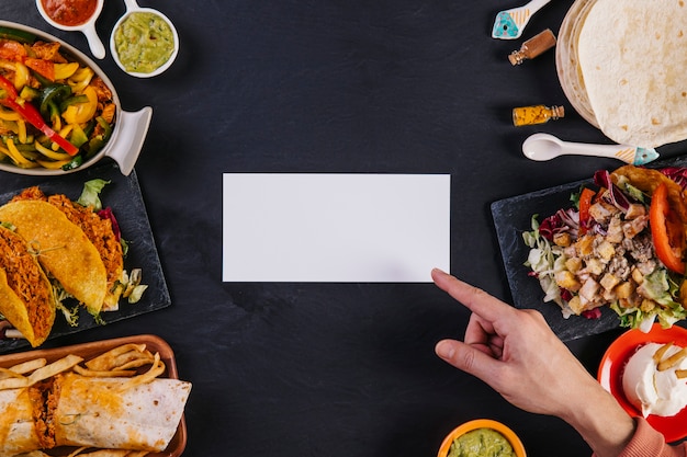 Mão apontando para papel perto da comida mexicana