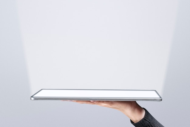 Foto grátis mão apresentando holograma invisível projetando-se da tecnologia avançada de tablet