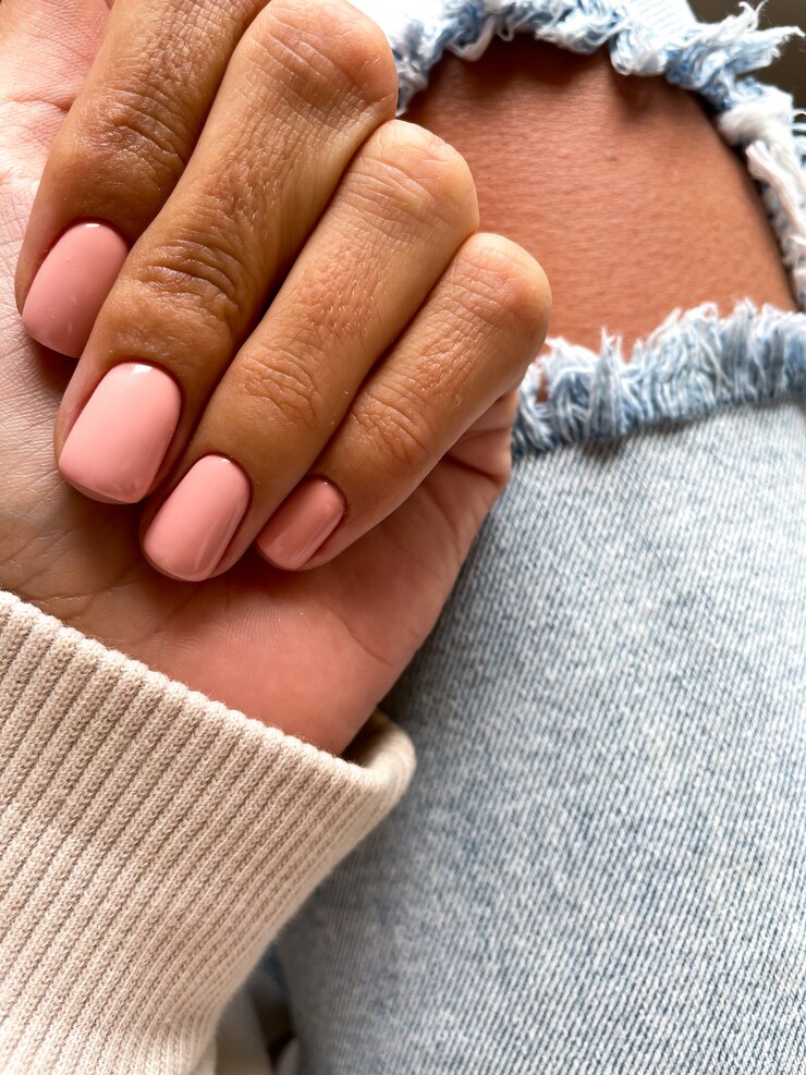 Foto grátis mão bronzeada de uma mulher com uma manicure bege-rosa suave, cobrindo com esmalte de gel