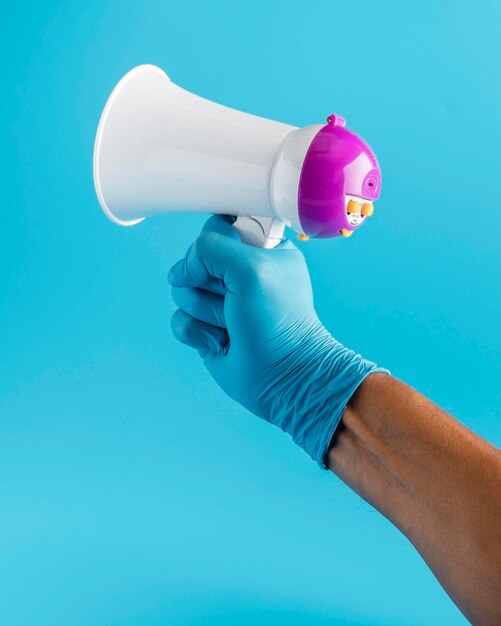 Mão com luva segurando megafone