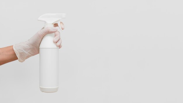 Mão com luva segurando solução de limpeza em frasco com espaço de cópia