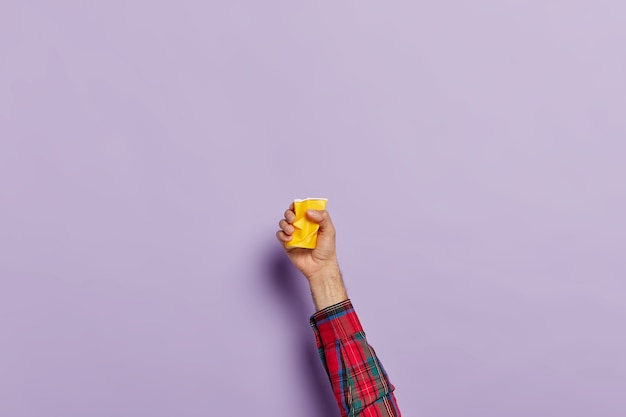 Foto grátis mão com uma xícara de café amassada vazia sobre o roxo