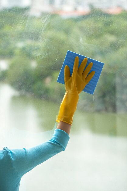 Mão cortada de mulher irreconhecível, limpeza de janela panorâmica