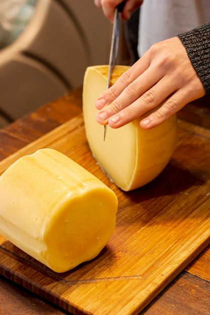 Mão cortando queijo delicioso