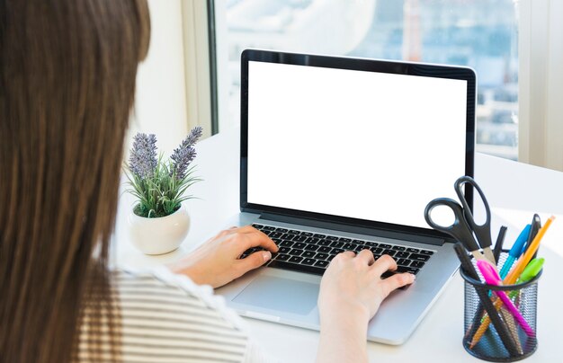 Mão da mulher de negócios usando laptop com tela branca em branco na mesa