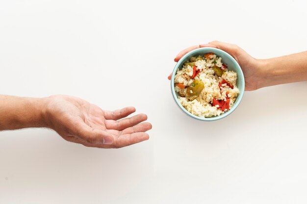 Mão dando tigela de comida para pessoa necessitada