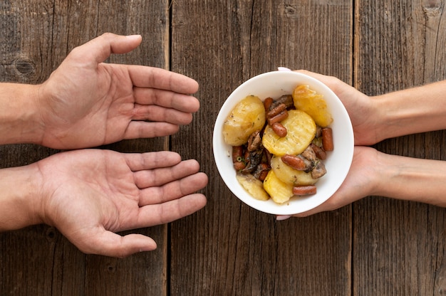 Foto grátis mão dando uma tigela de comida doada para uma pessoa necessitada