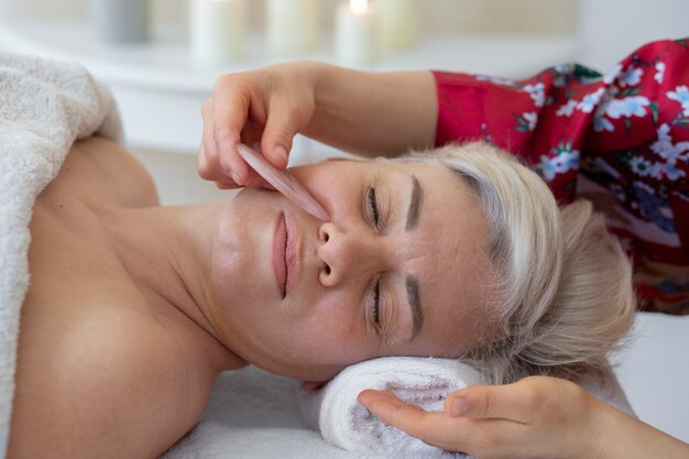 Mão de alto ângulo usando gua sha para tratamento