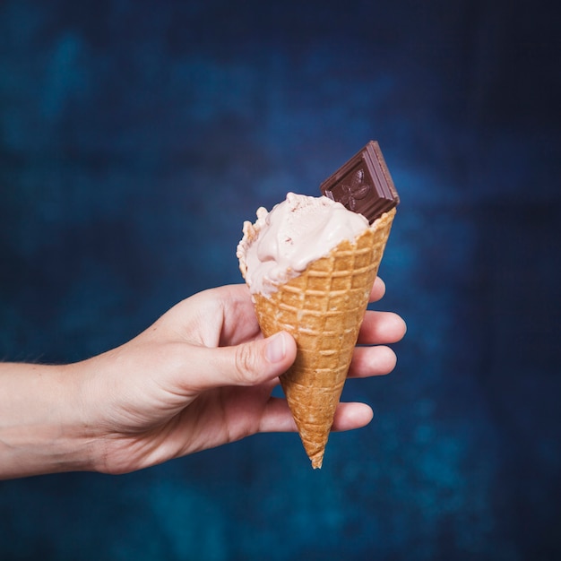 Mão de colheita segurando o cone com sorvete