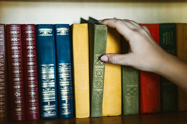 Mão de colheita tomando livro vintage