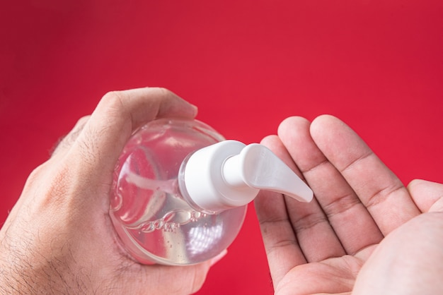 Foto grátis mão de homem em recipiente com gel de álcool no vermelho