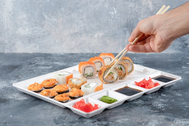 Mão de homem pegando rolinho de sushi quente à milanesa com pauzinho